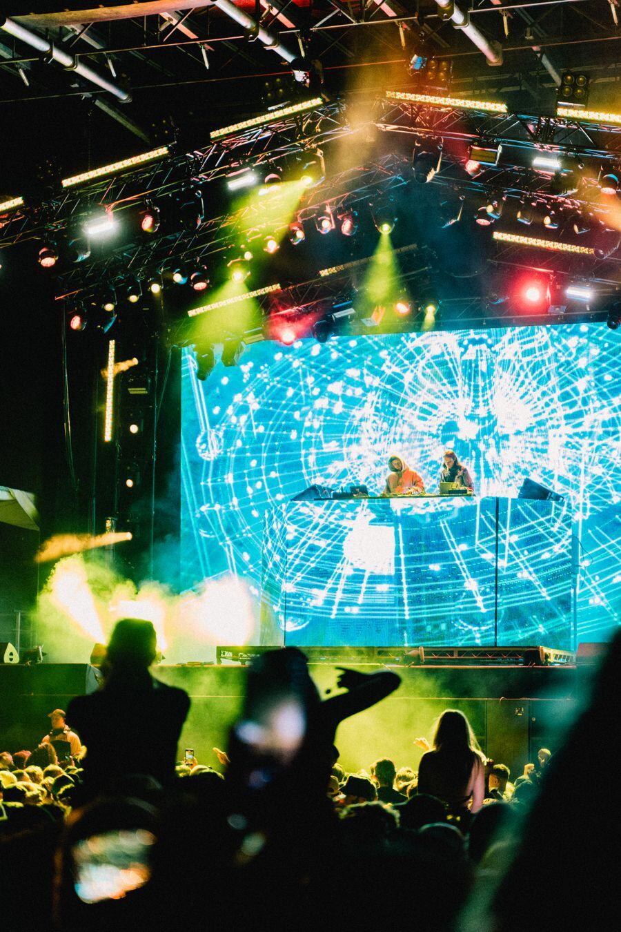 A crowd under green and blue stage lights at a concert