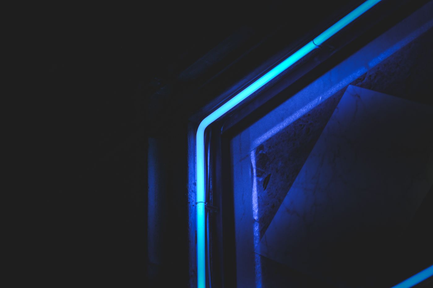 A thin blue neon light glowing in a dark room