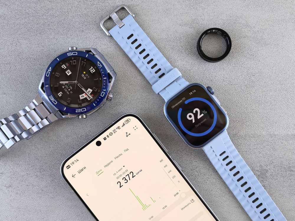 A smartwatch, a ring and a phone laid out on a table
