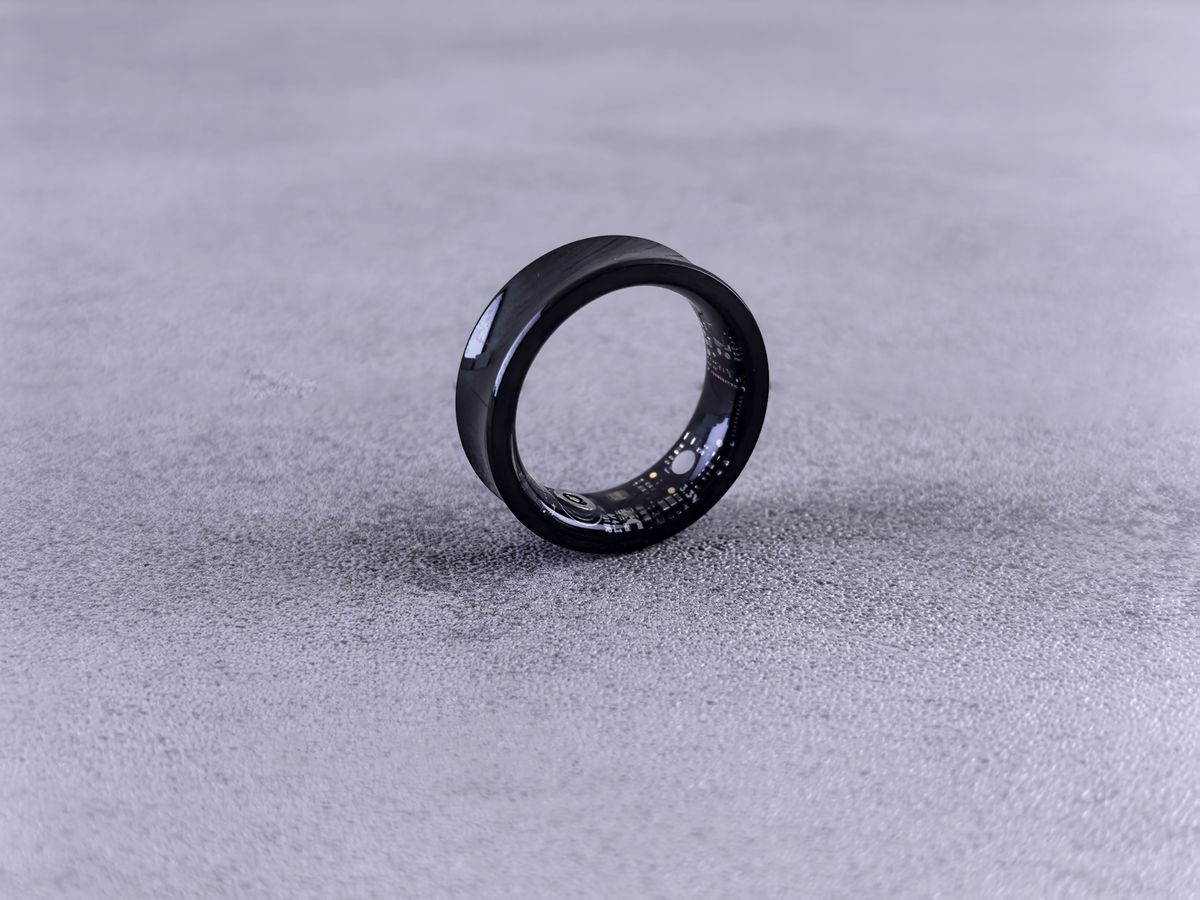 A black smart ring resting on a concrete surface