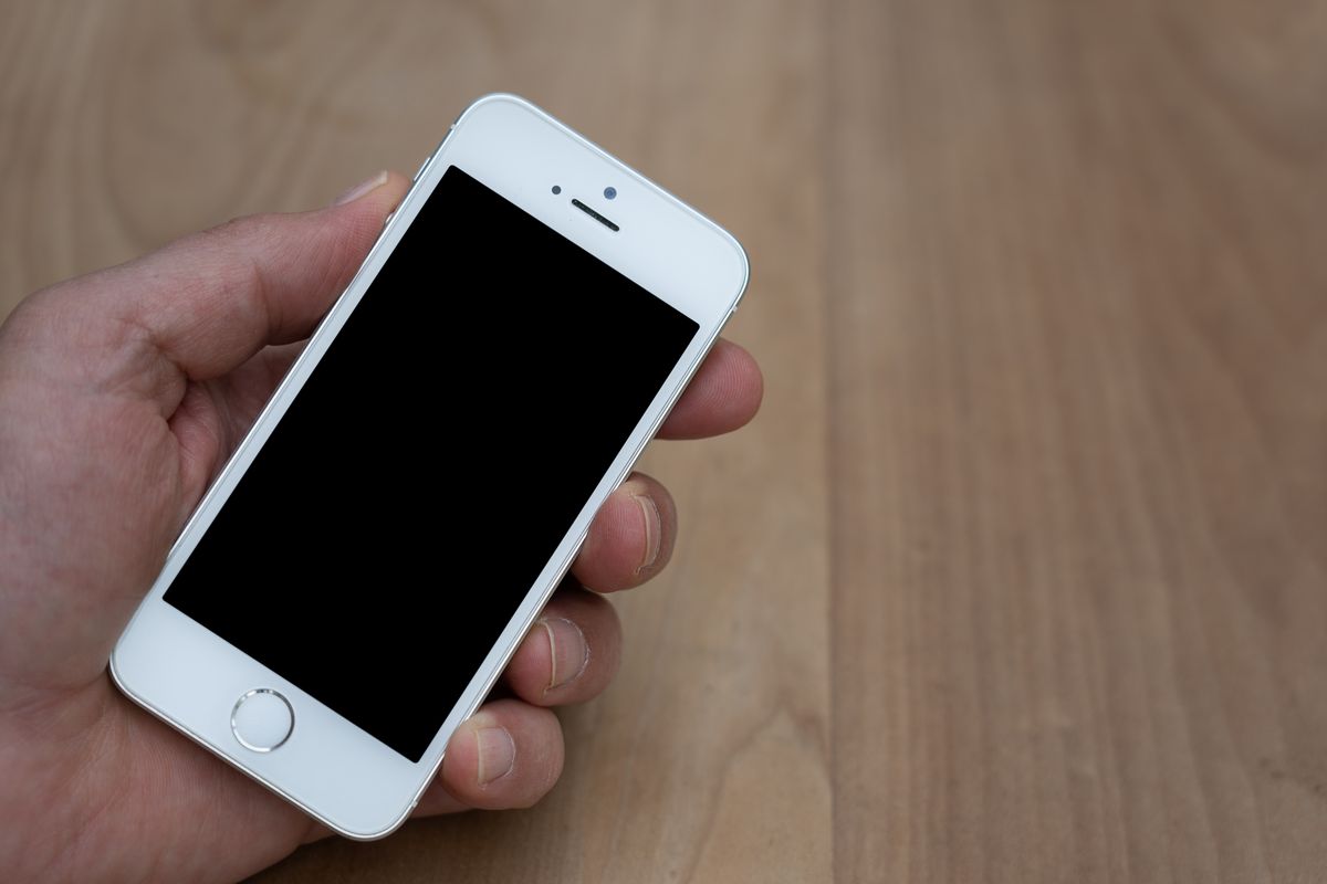 A hand holding a phone with a dark screen