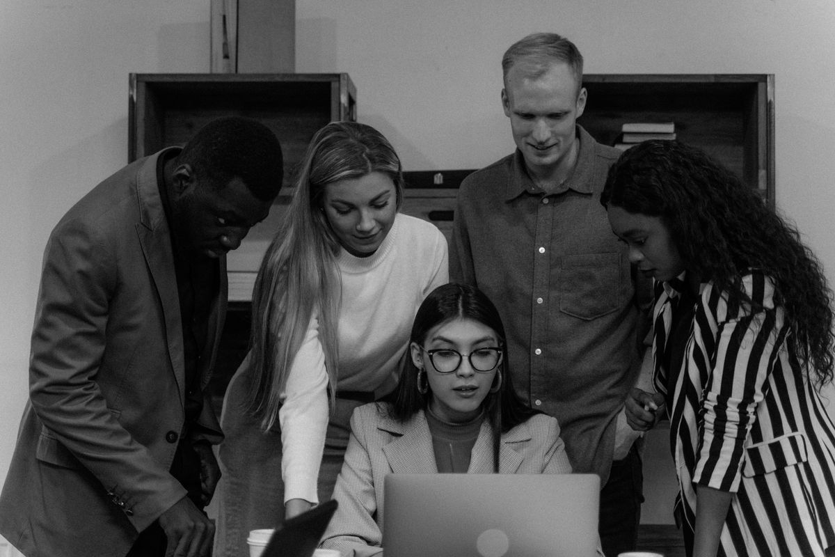 Colleagues gathered around a laptop, in black and white