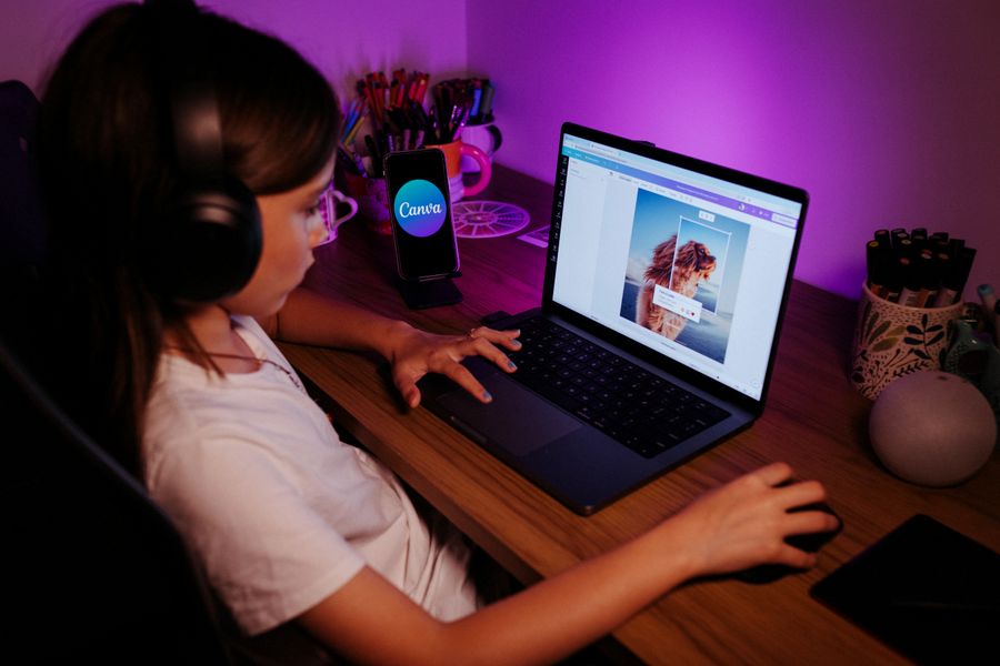 A student coding on a laptop in purple light
