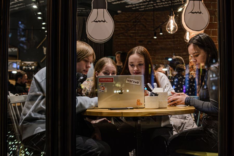 Friends working on laptops together in a café