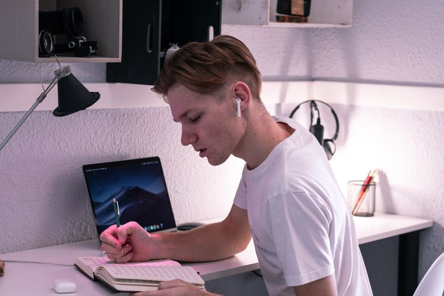 A student taking notes beside a laptop