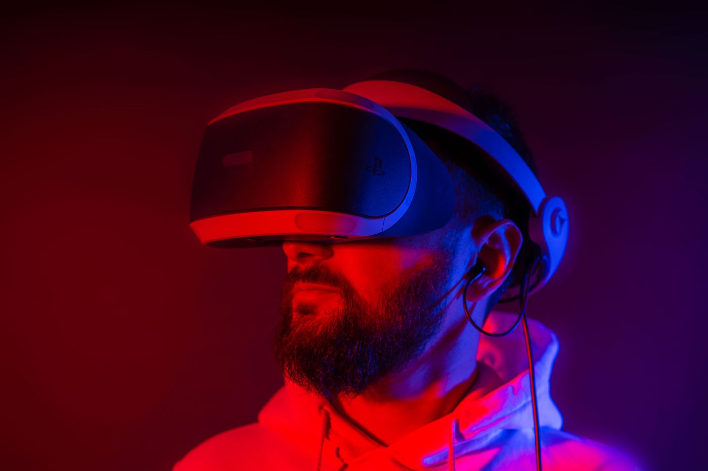 A bearded man wearing a VR headset, lit in red and violet