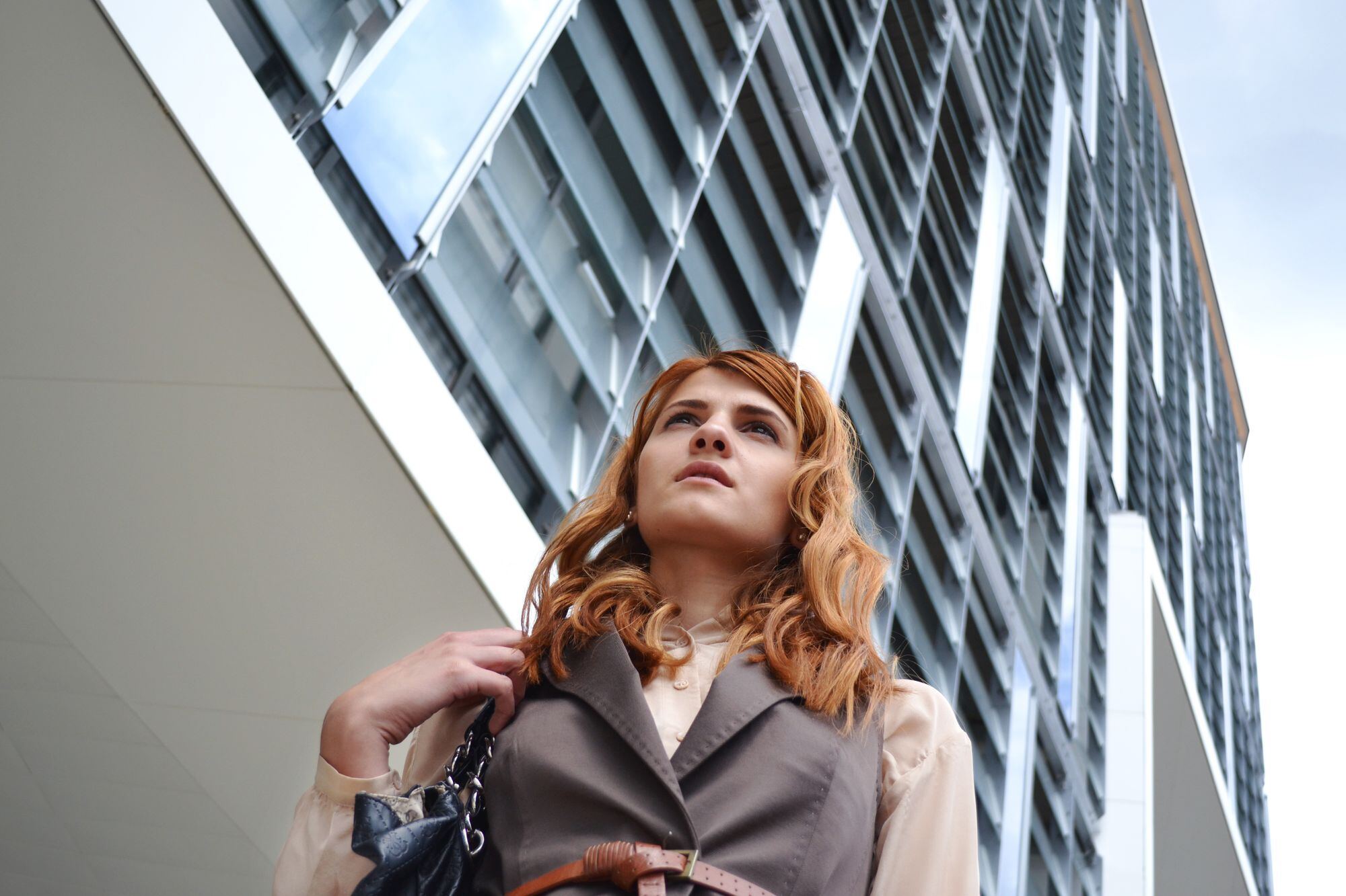 A woman looking up at the sky between glass buildings