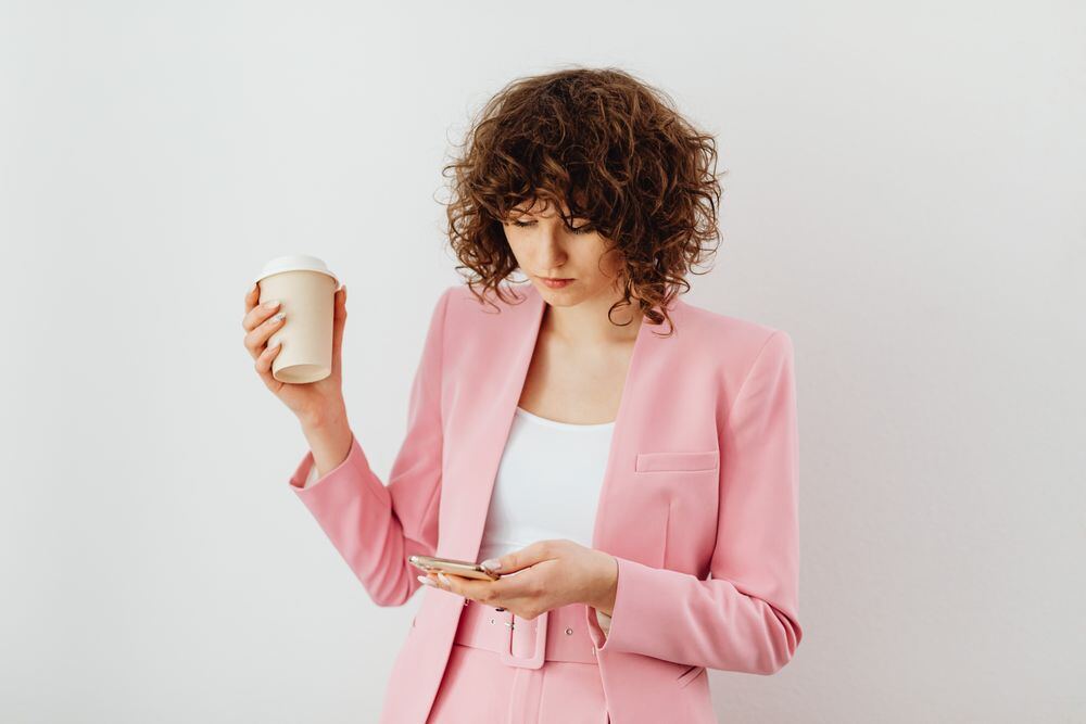 A woman in a pink blazer checking her phone