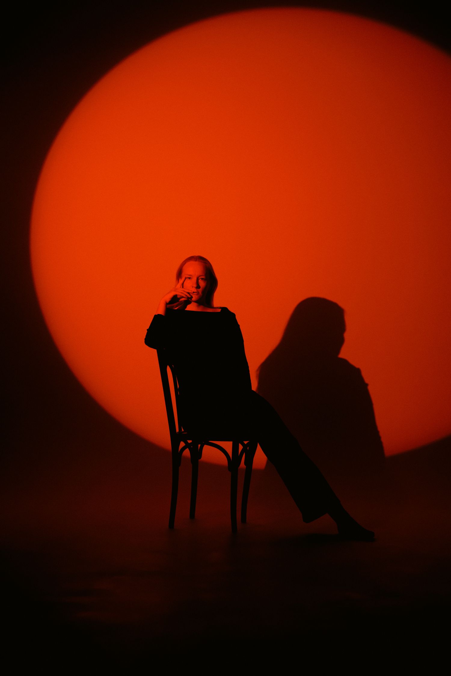 A woman seated on a chair in front of a large orange circle of light