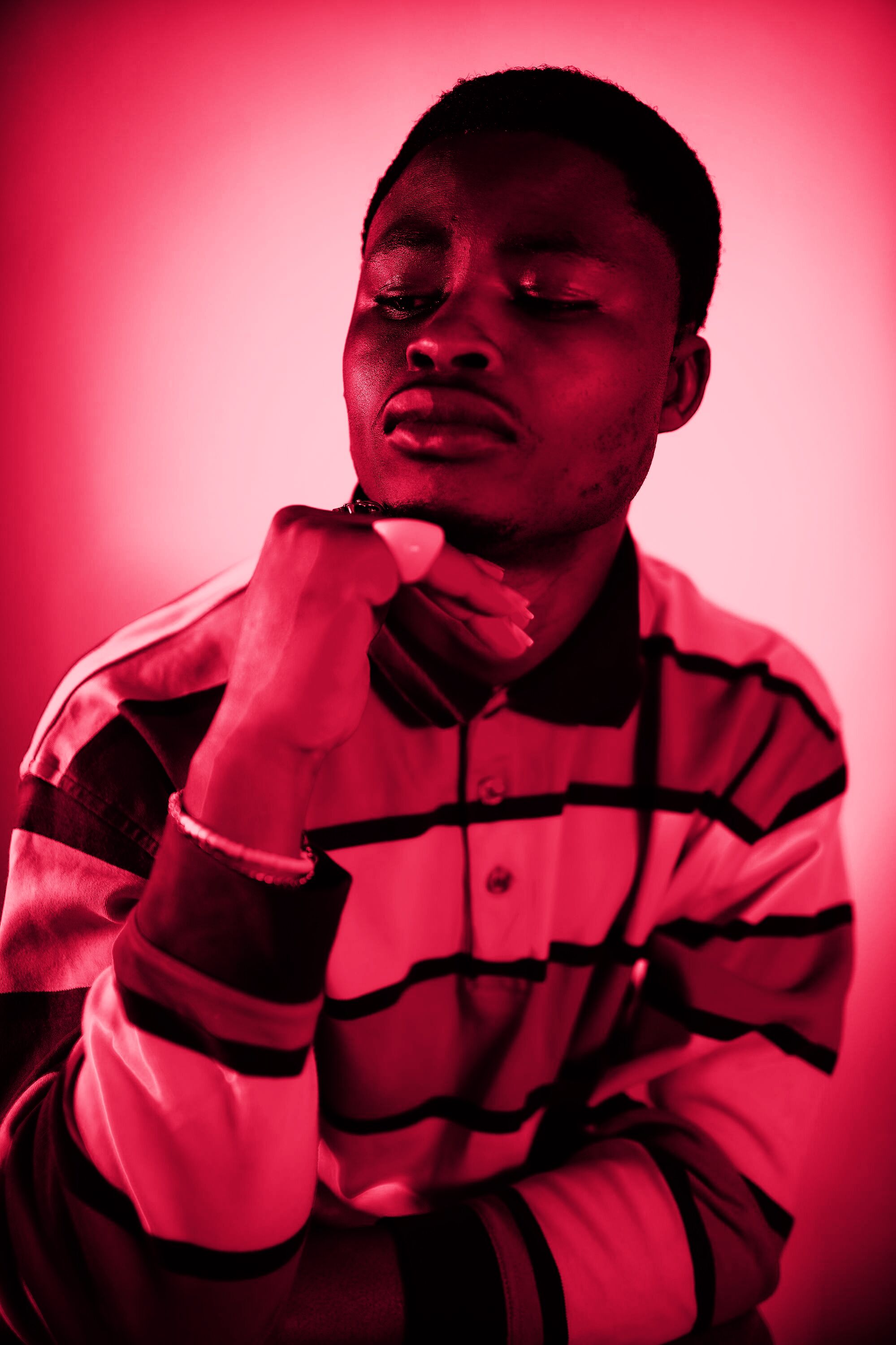 A man in red light lifting his chin towards the camera