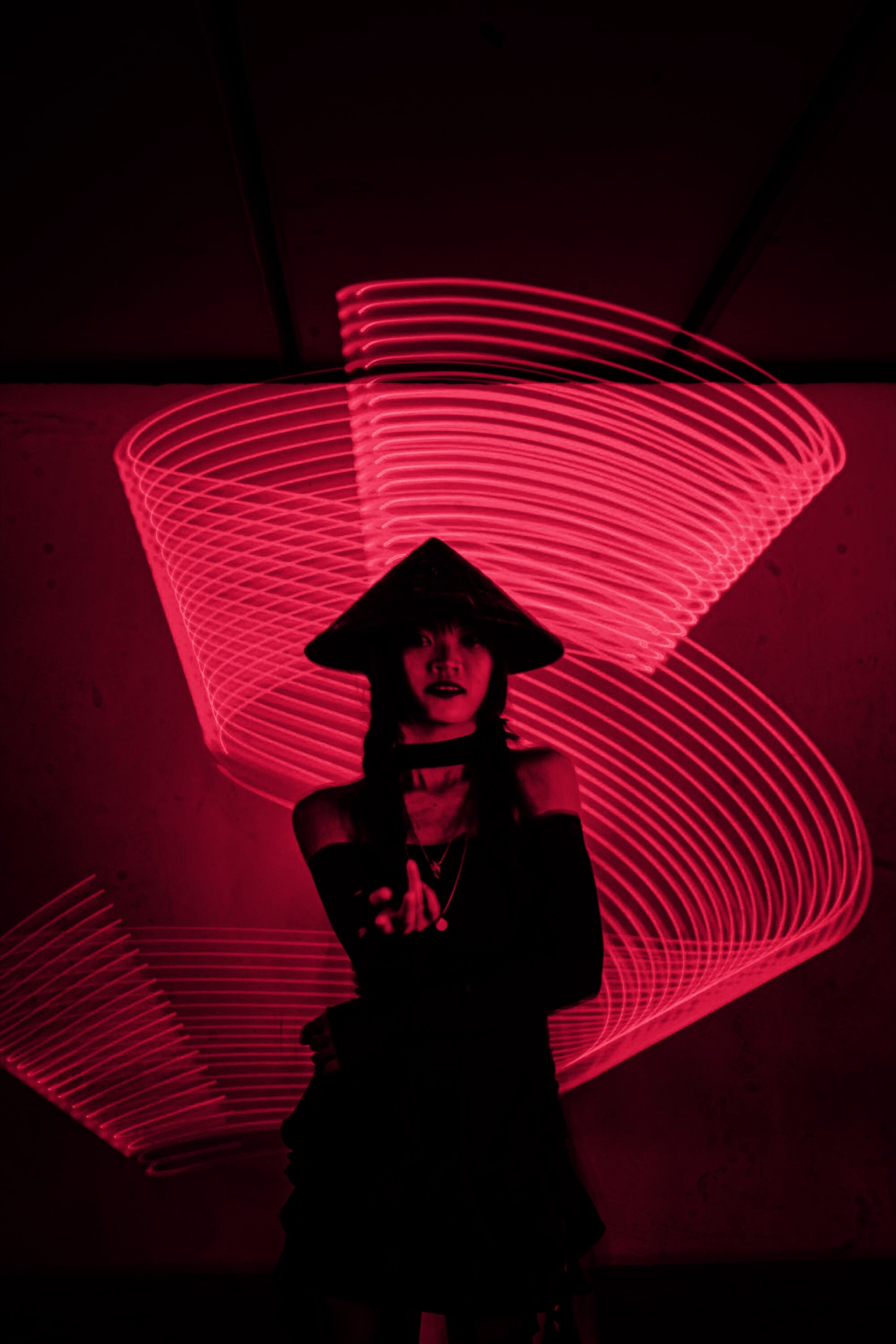 A woman in a wide hat inside rings of red light