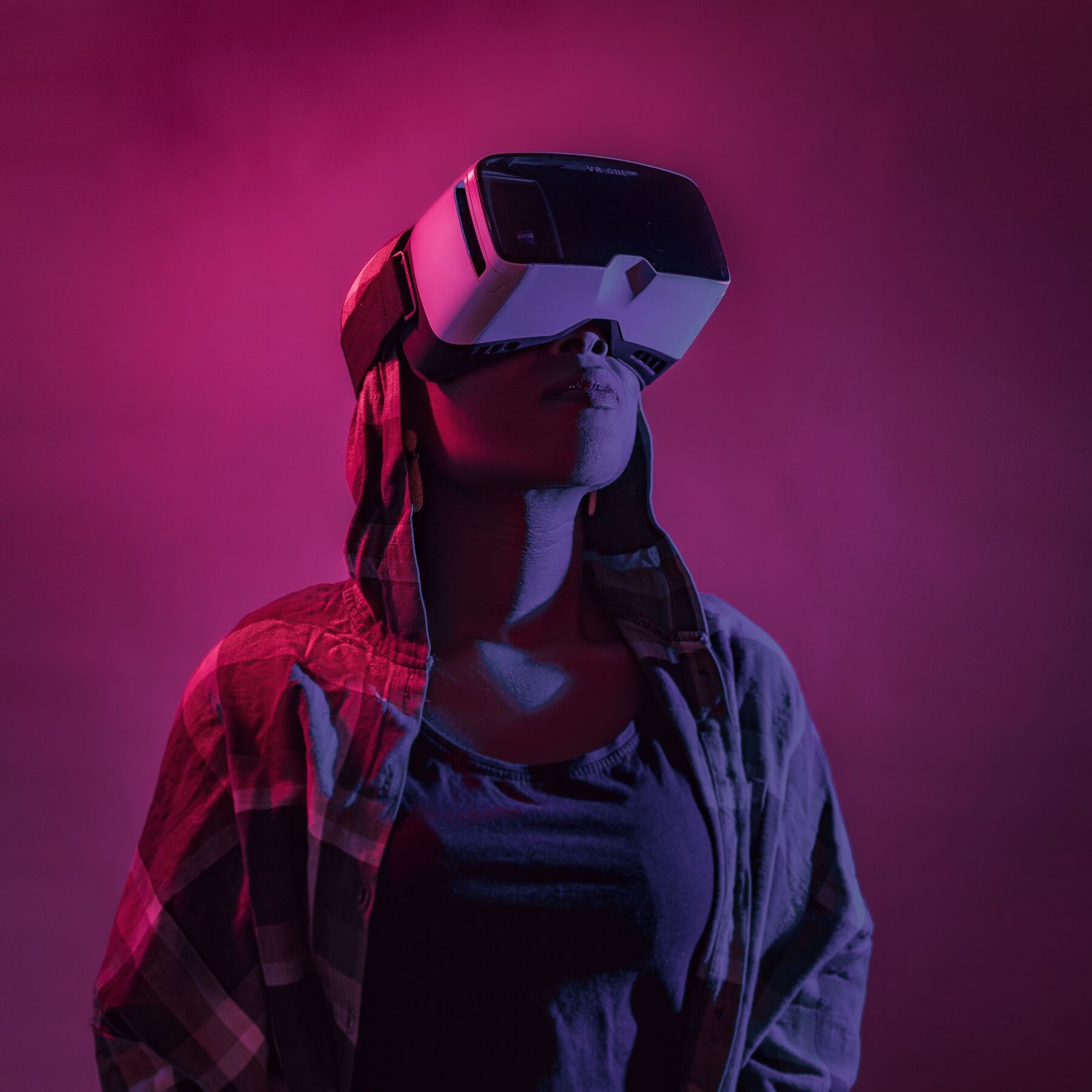A woman wearing a white VR headset in pink neon light