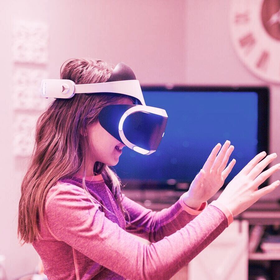A girl wearing a headset in her living room, reaching into a virtual scene